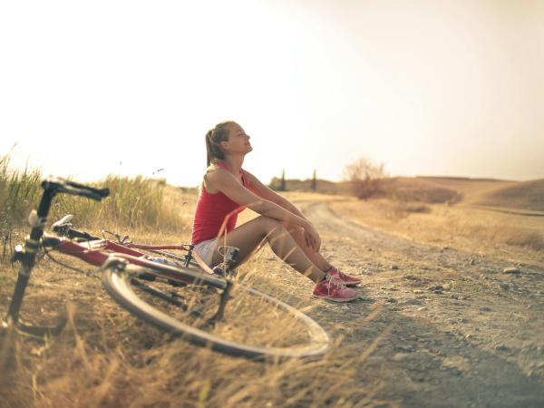 Foto door Andrea Piacquadio: https://www.pexels.com/nl-nl/foto/sportieve-vrouw-met-fiets-die-op-plattelandsweg-in-zonlicht-rust-3771836/